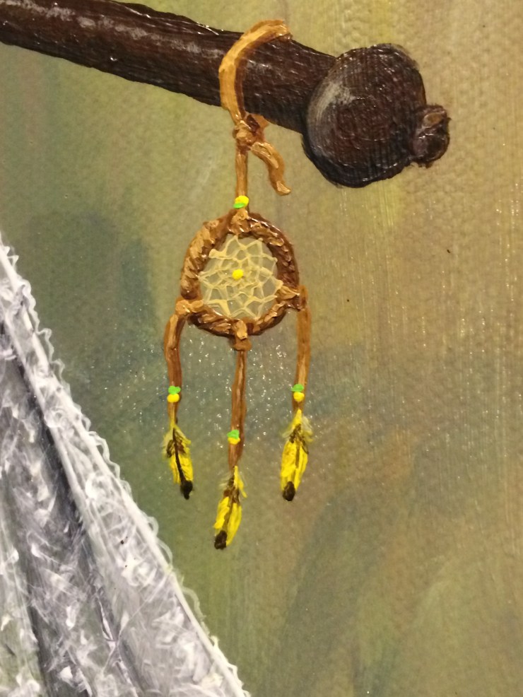 A close up detail of a painting shows a small dream catcher hung with yellow canary feathers. The texture of the canvas and brush strokes are visible.