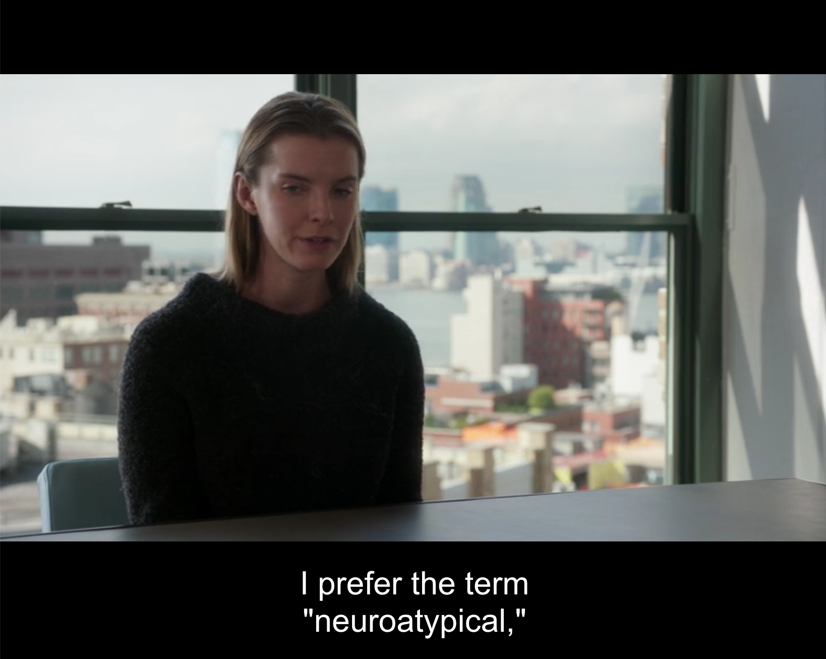 Fiona sits rigidly at a conference table with her hands folded in her lap. A view of New York is visible through the window behind her. A subtitle reads: "I prefer the term "neuro-a-typical" (Elementary. 2016a).
